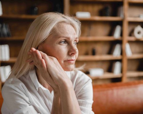 Stressed sad tired exhausted caucasian middle-aged mature businesswoman freelancer relaxing on the couch sofa, thinking about family marriage work problems at work office