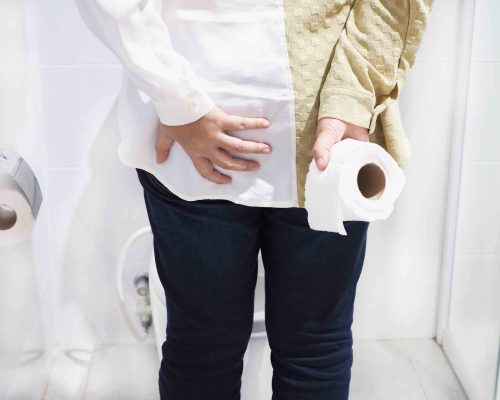 Young woman with hemorrhoids visiting restroom. Health concept.